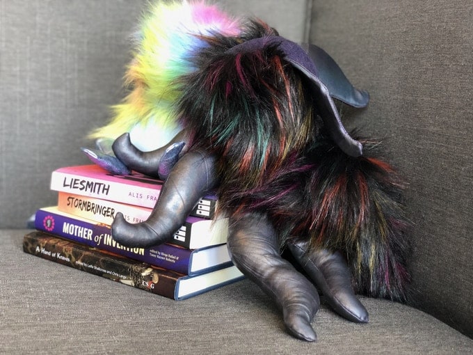 Plushie tentacle beasts sitting atop a pile of books available via the UO Kickstarter.